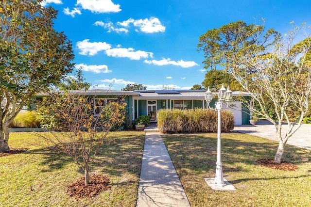 single story home with a front yard and solar panels