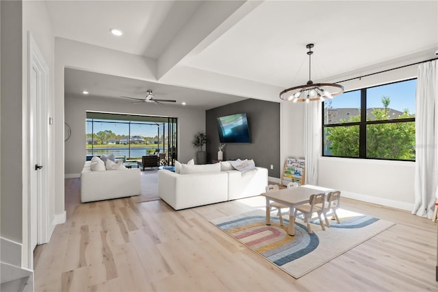 living room with ceiling fan with notable chandelier and light hardwood / wood-style floors