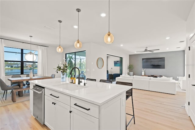 kitchen featuring pendant lighting, sink, white cabinetry, a wealth of natural light, and an island with sink