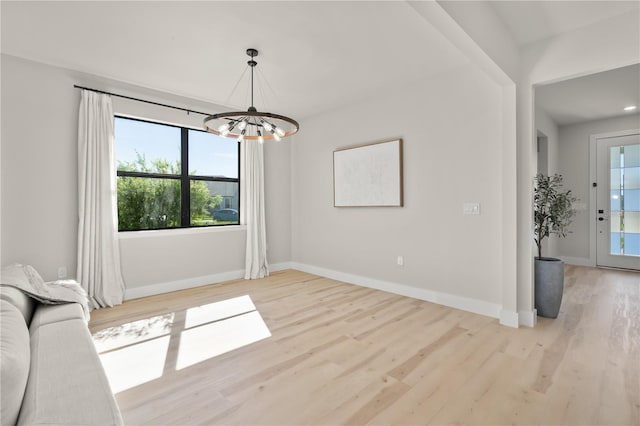 unfurnished dining area featuring light hardwood / wood-style flooring and an inviting chandelier