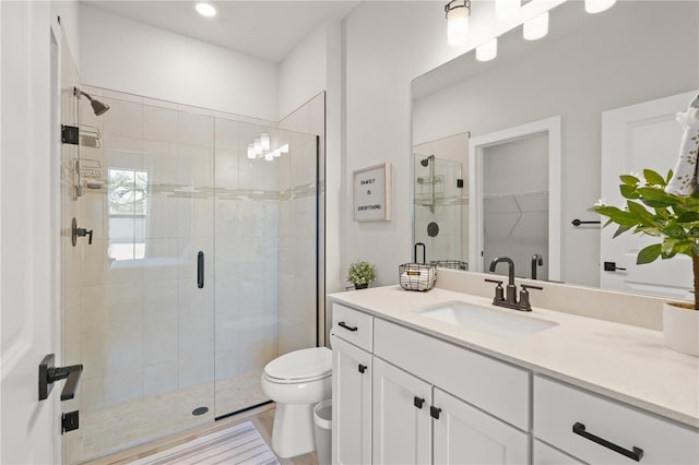 bathroom with a shower with shower door, toilet, and vanity