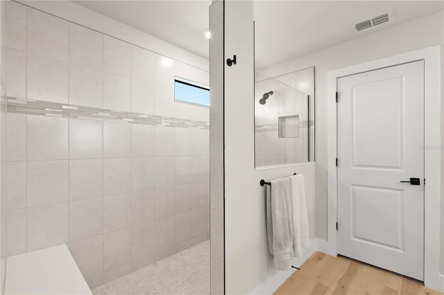 bathroom featuring hardwood / wood-style floors and a tile shower