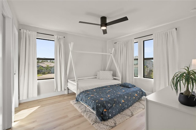 bedroom featuring ceiling fan, light hardwood / wood-style flooring, and multiple windows