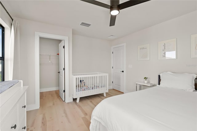 bedroom featuring ceiling fan, a spacious closet, a closet, and light wood-type flooring