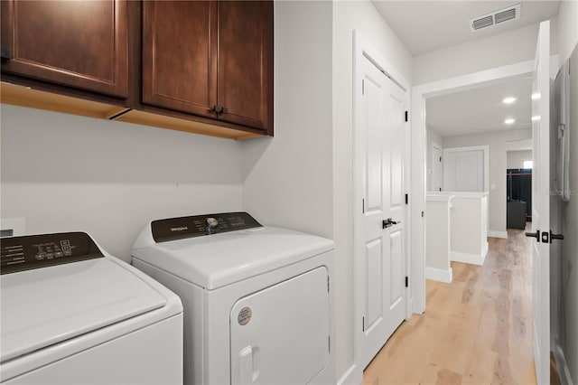 laundry area with cabinets, light hardwood / wood-style flooring, and independent washer and dryer