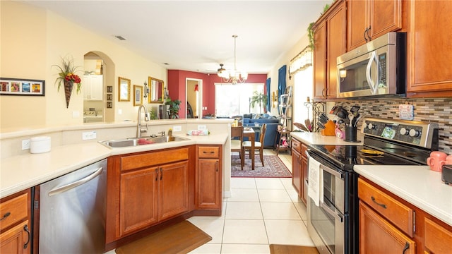 kitchen featuring sink, appliances with stainless steel finishes, hanging light fixtures, light tile patterned flooring, and a chandelier