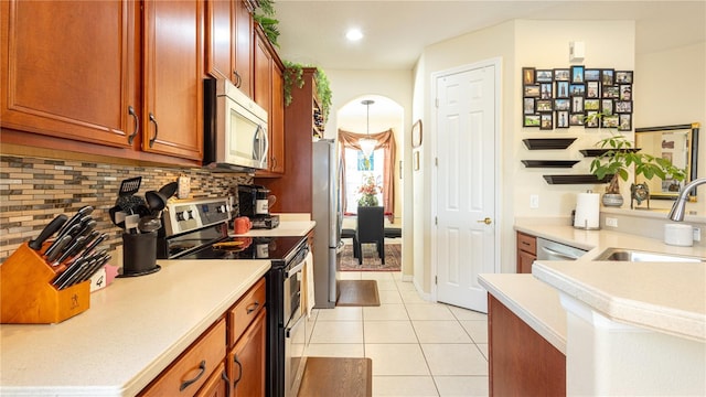 kitchen with light tile patterned floors, stainless steel appliances, sink, and backsplash