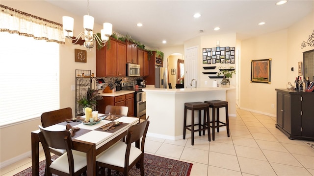 kitchen with decorative backsplash, hanging light fixtures, light tile patterned floors, stainless steel appliances, and an inviting chandelier