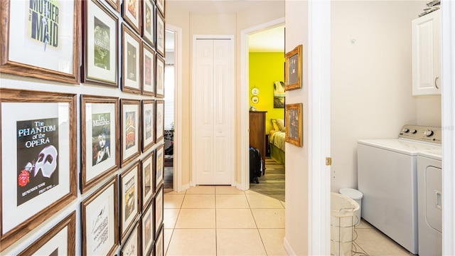 laundry area featuring light tile patterned floors, washer and clothes dryer, and cabinets