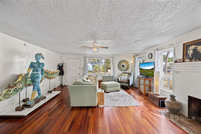 living room with ceiling fan, dark wood-type flooring, and a textured ceiling