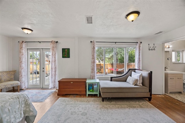 interior space featuring access to exterior, wood-type flooring, french doors, and a textured ceiling