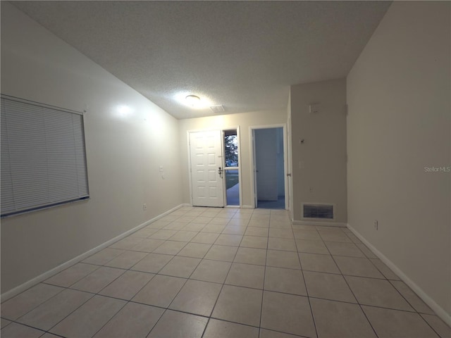 unfurnished room featuring a textured ceiling and light tile patterned floors