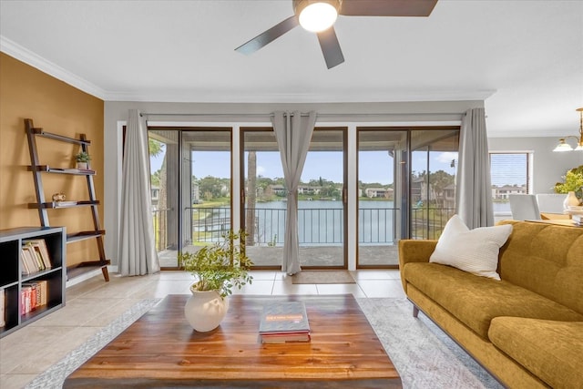 living room featuring ceiling fan with notable chandelier, light tile patterned flooring, ornamental molding, and a water view