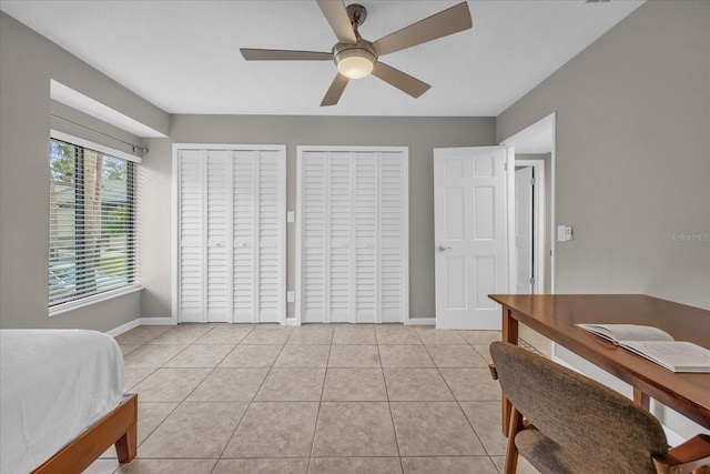 tiled bedroom with two closets and ceiling fan