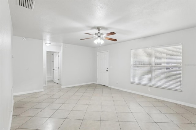 empty room with ceiling fan, light tile patterned floors, and a textured ceiling