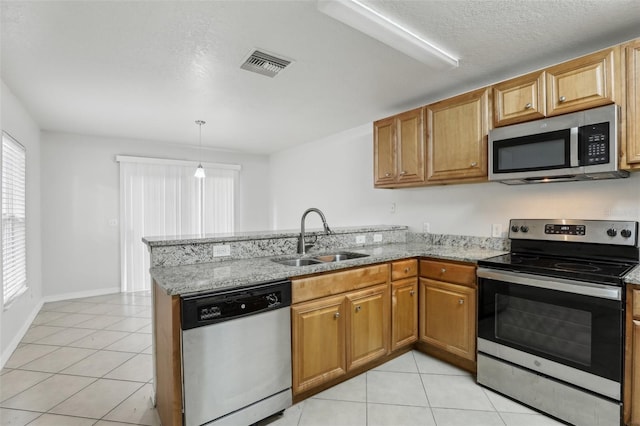 kitchen with kitchen peninsula, appliances with stainless steel finishes, sink, light stone countertops, and light tile patterned flooring