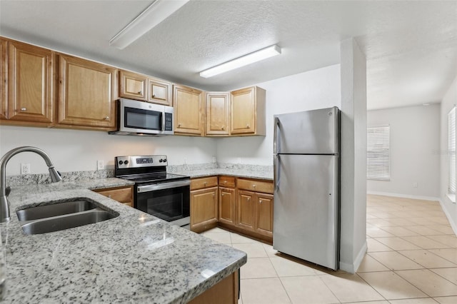 kitchen featuring sink, light tile patterned floors, light stone countertops, a textured ceiling, and stainless steel appliances