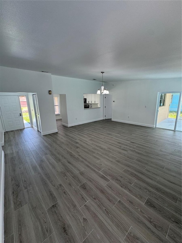 unfurnished living room with dark hardwood / wood-style flooring and a chandelier