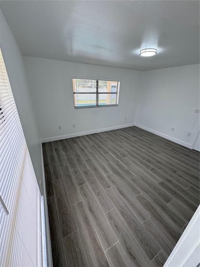 unfurnished room featuring a textured ceiling and dark hardwood / wood-style floors