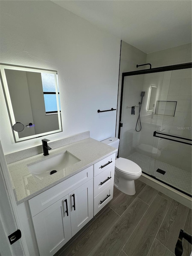 bathroom with an enclosed shower, vanity, and toilet