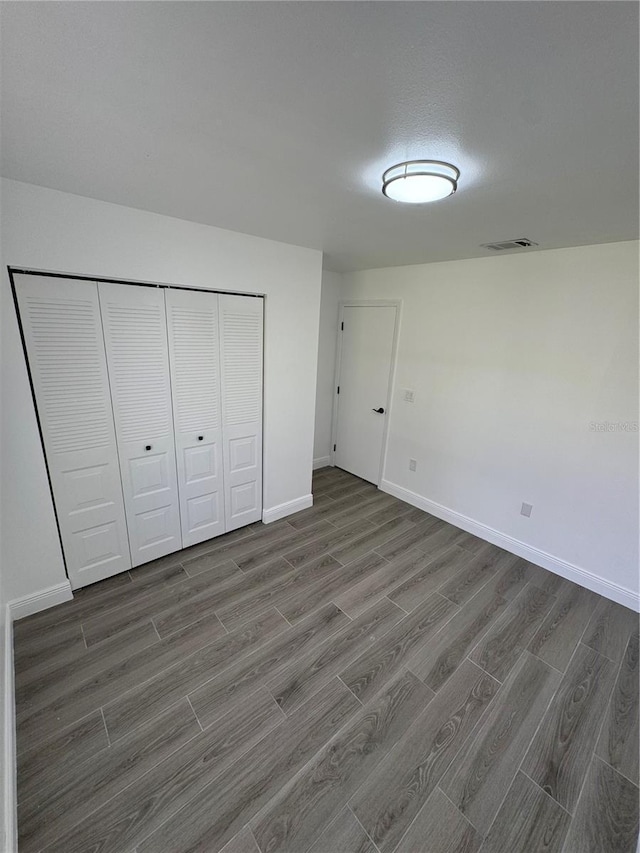 unfurnished bedroom with dark hardwood / wood-style floors and a closet