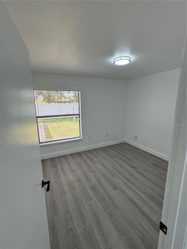 spare room featuring wood-type flooring and a textured ceiling