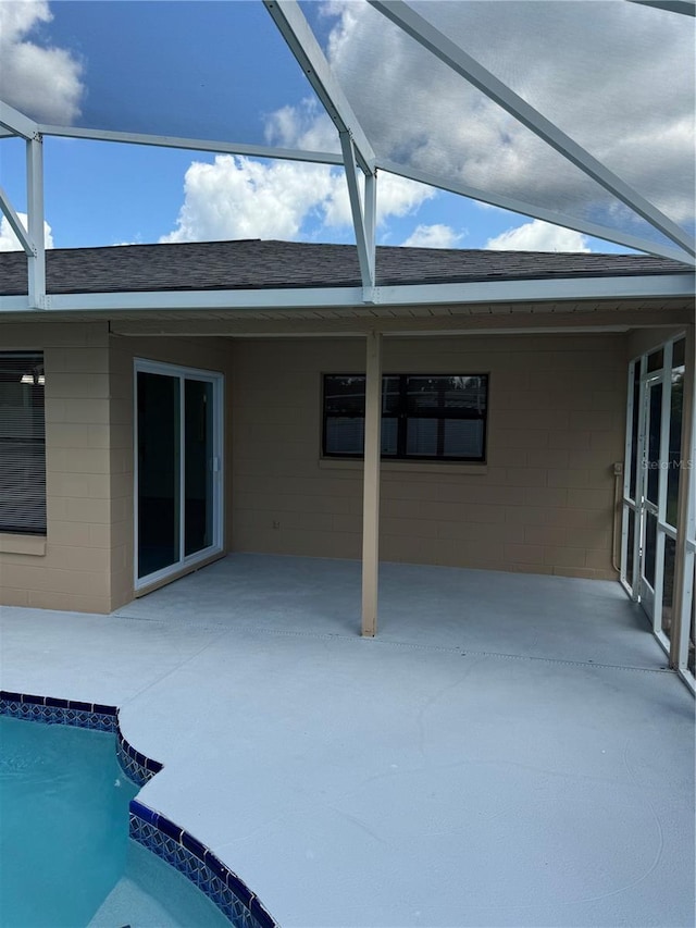 view of pool with glass enclosure and a patio area