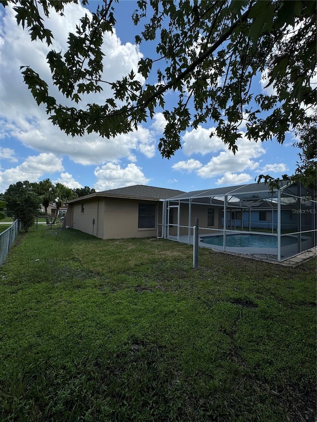 back of house with glass enclosure, a fenced in pool, and a yard