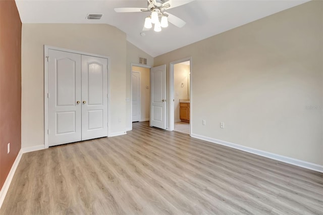 unfurnished bedroom featuring ensuite bath, a closet, light hardwood / wood-style flooring, ceiling fan, and lofted ceiling