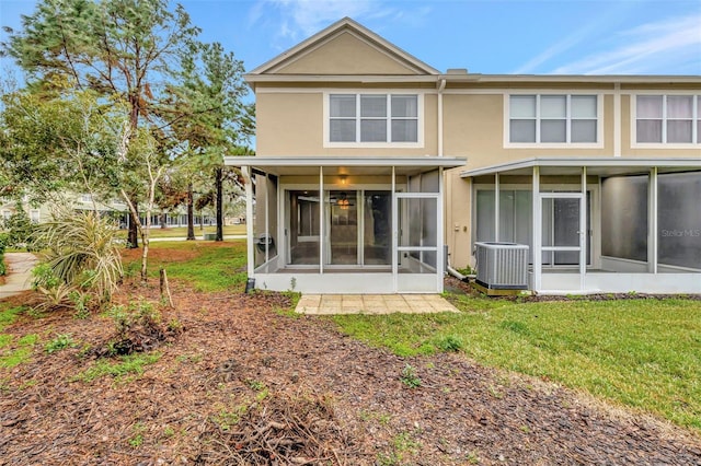 back of house featuring central AC unit, a lawn, and a sunroom