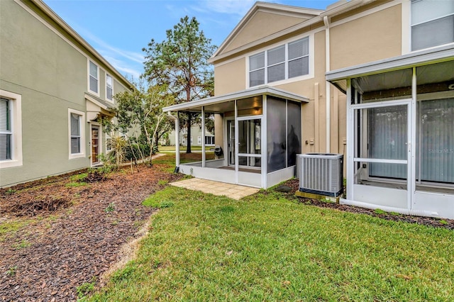 back of property featuring a sunroom, a yard, and central AC unit