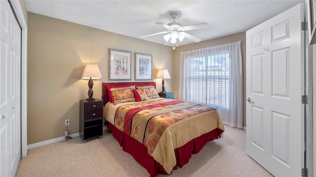 bedroom featuring ceiling fan, light colored carpet, and a textured ceiling