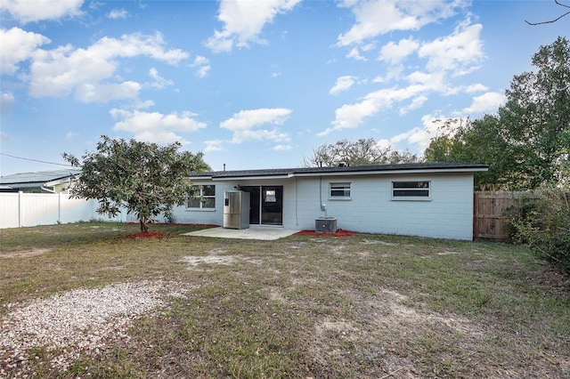 rear view of property featuring a yard, a patio area, and central AC