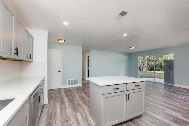 kitchen with gray cabinets, a kitchen island, a textured ceiling, and light hardwood / wood-style floors