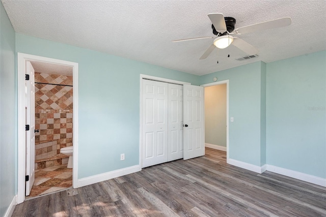 unfurnished bedroom featuring ensuite bathroom, hardwood / wood-style floors, a textured ceiling, and a closet