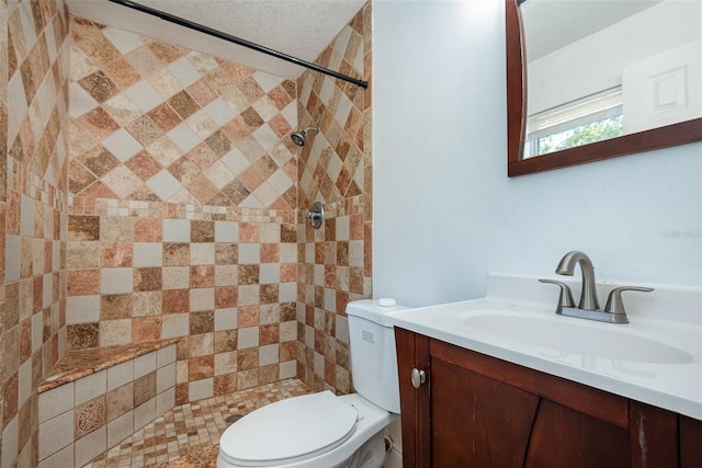 bathroom with vanity, a tile shower, and toilet