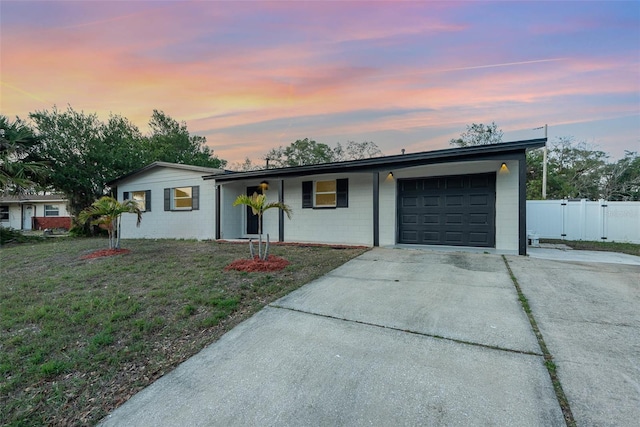 single story home featuring a garage and a lawn