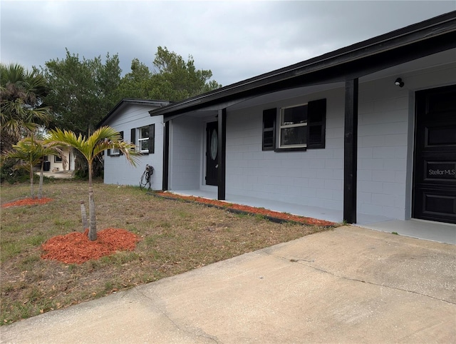 view of front of house with concrete block siding and a front lawn