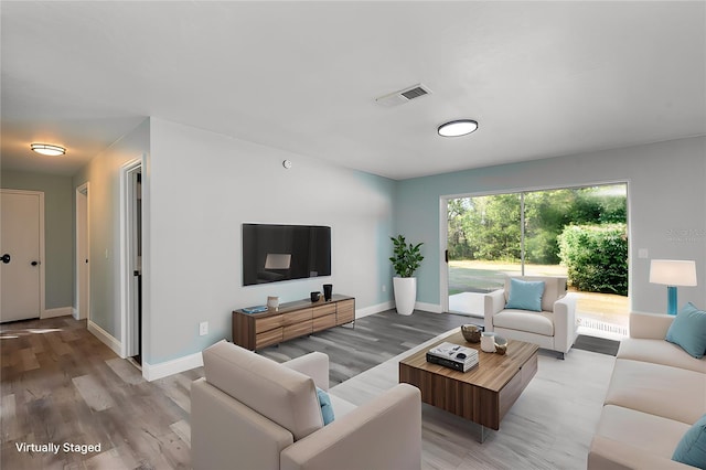 living area featuring light wood finished floors, visible vents, and baseboards