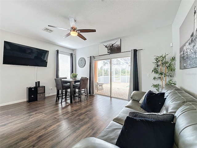 living room with ceiling fan, dark wood-type flooring, and a textured ceiling