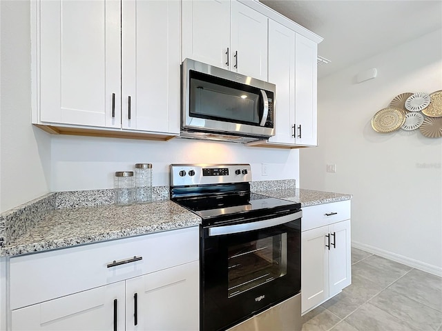 kitchen featuring light stone counters, white cabinetry, light tile patterned floors, and stainless steel appliances