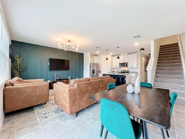 living room with a notable chandelier, light tile patterned floors, and sink