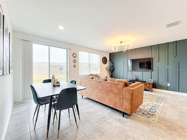 living room with a textured ceiling, a chandelier, and light tile patterned floors