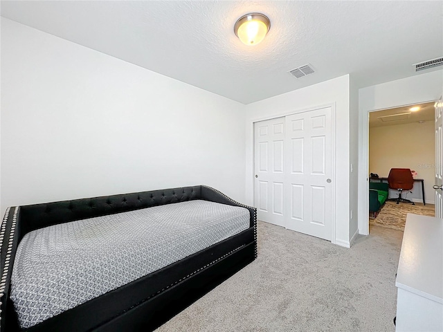 carpeted bedroom featuring a textured ceiling and a closet