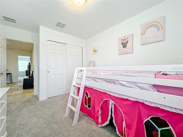 bedroom with a textured ceiling, carpet floors, and a closet