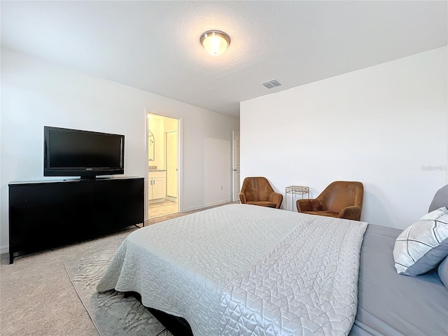 bedroom with connected bathroom, light carpet, and a textured ceiling