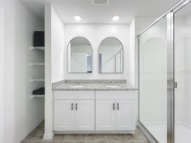 bathroom with tile patterned floors, walk in shower, and vanity