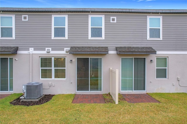 rear view of property with central AC unit and a yard