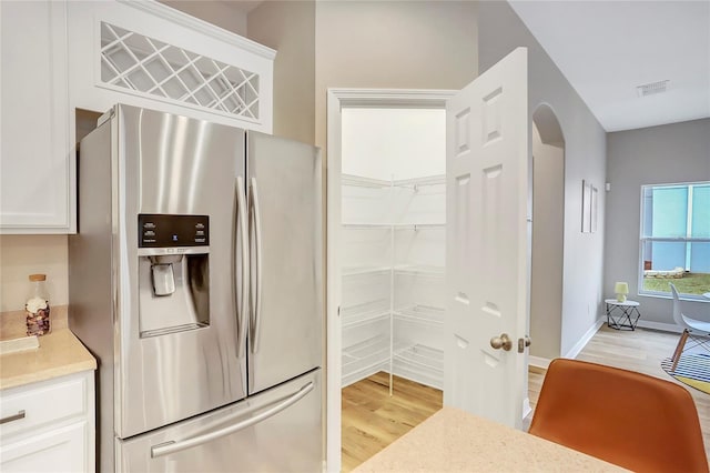 kitchen featuring white cabinetry, stainless steel fridge with ice dispenser, and light hardwood / wood-style flooring