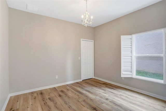 empty room with light hardwood / wood-style floors and a chandelier